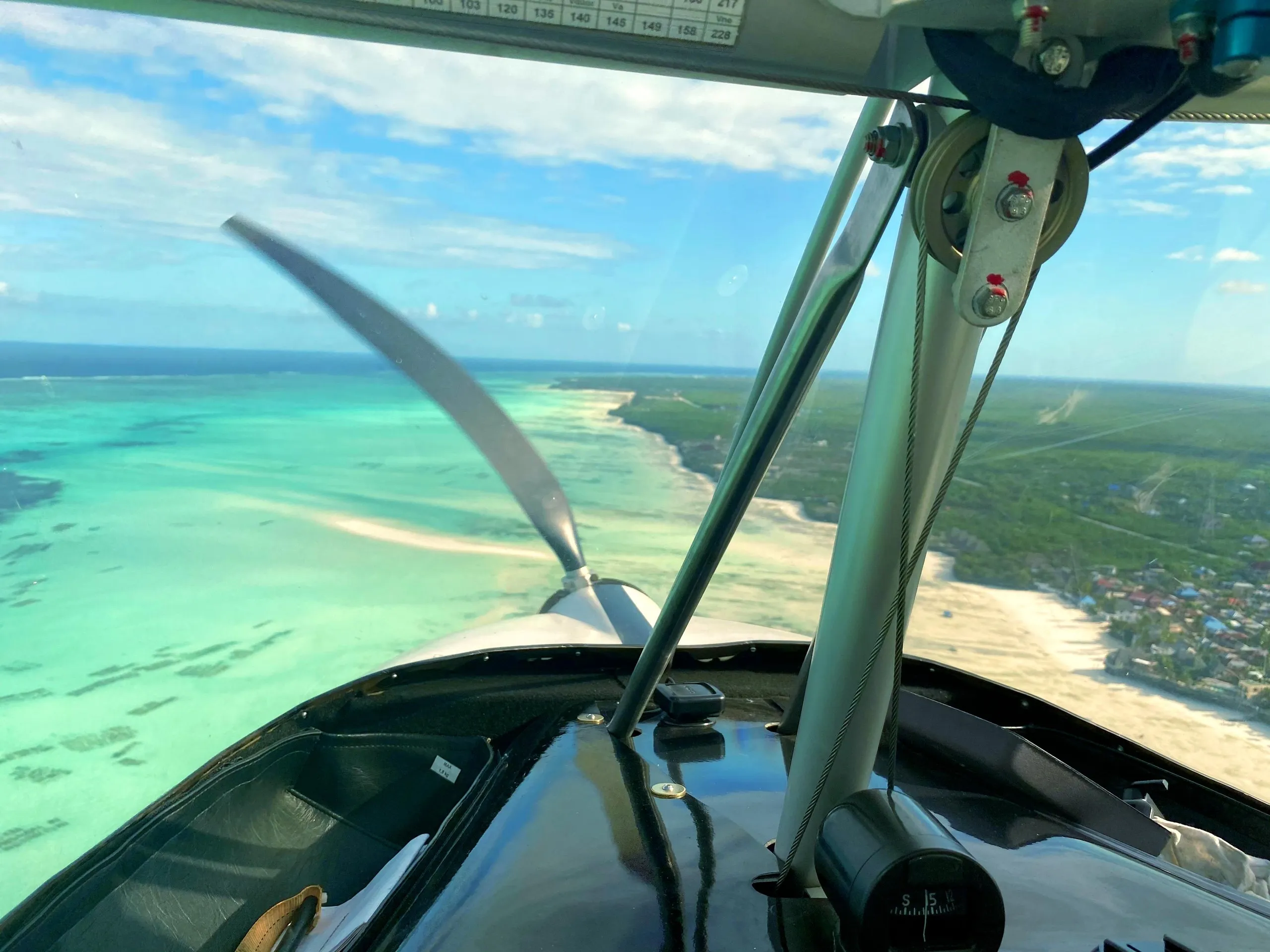 Turquoise lagoon and white beaches of Zanzibar seen through the propeller of a ZRP aircraft