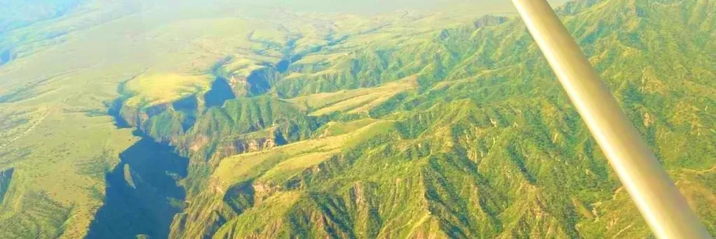 Aerial view of green hills and a canyon from a light aircraft